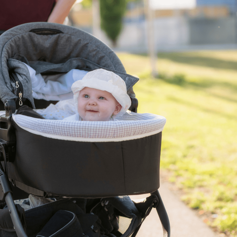 Baby wearing a white sun hat in a pram 